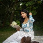 Serene portrait of a woman in a floral dress reading outdoors in Kolkata, India.